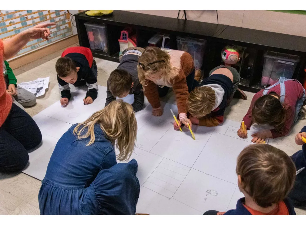 Kinderen tekenen samen op een groot blad