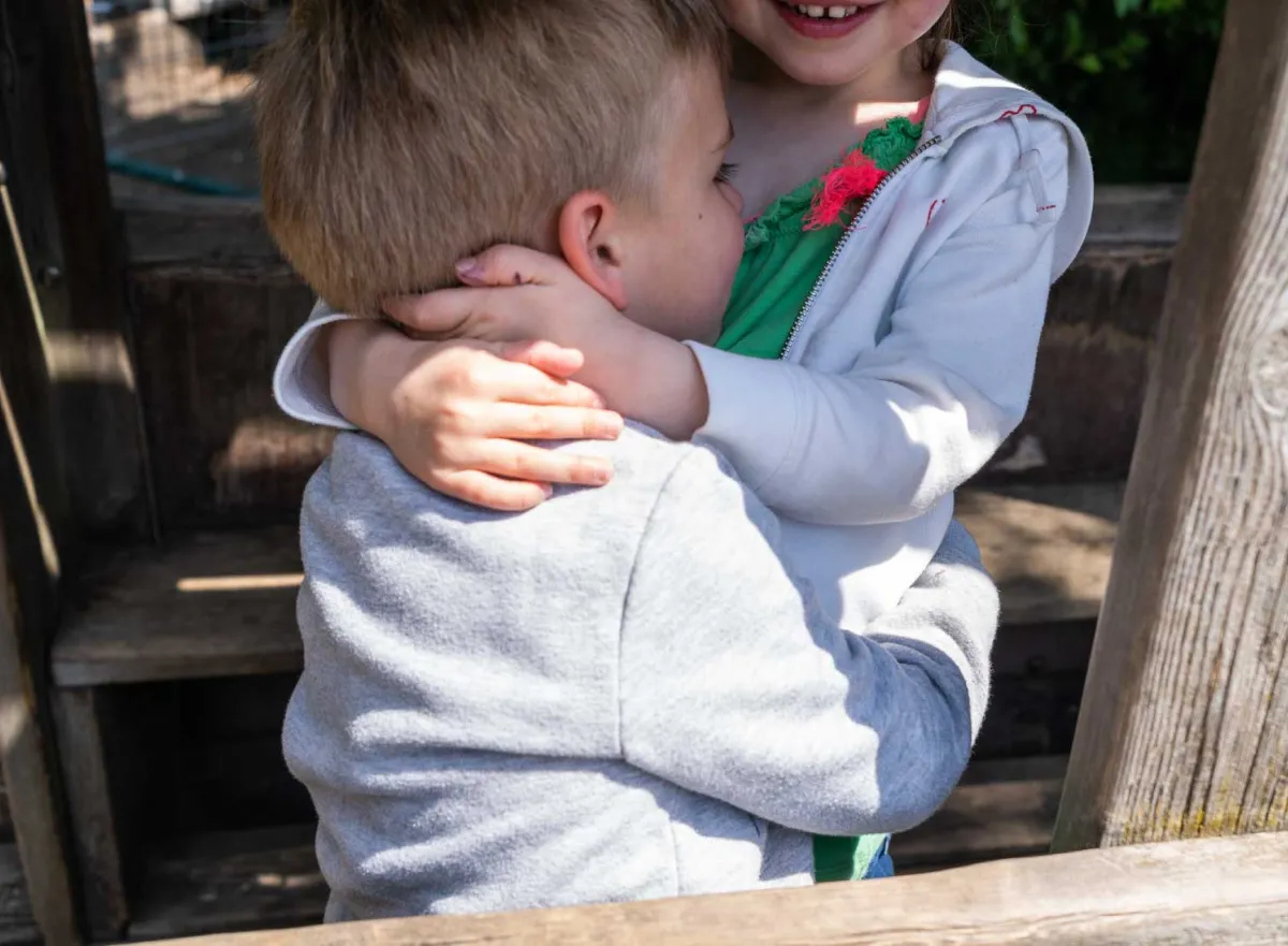 twee kinderen geven elkaar een knuffel op de speelplaats
