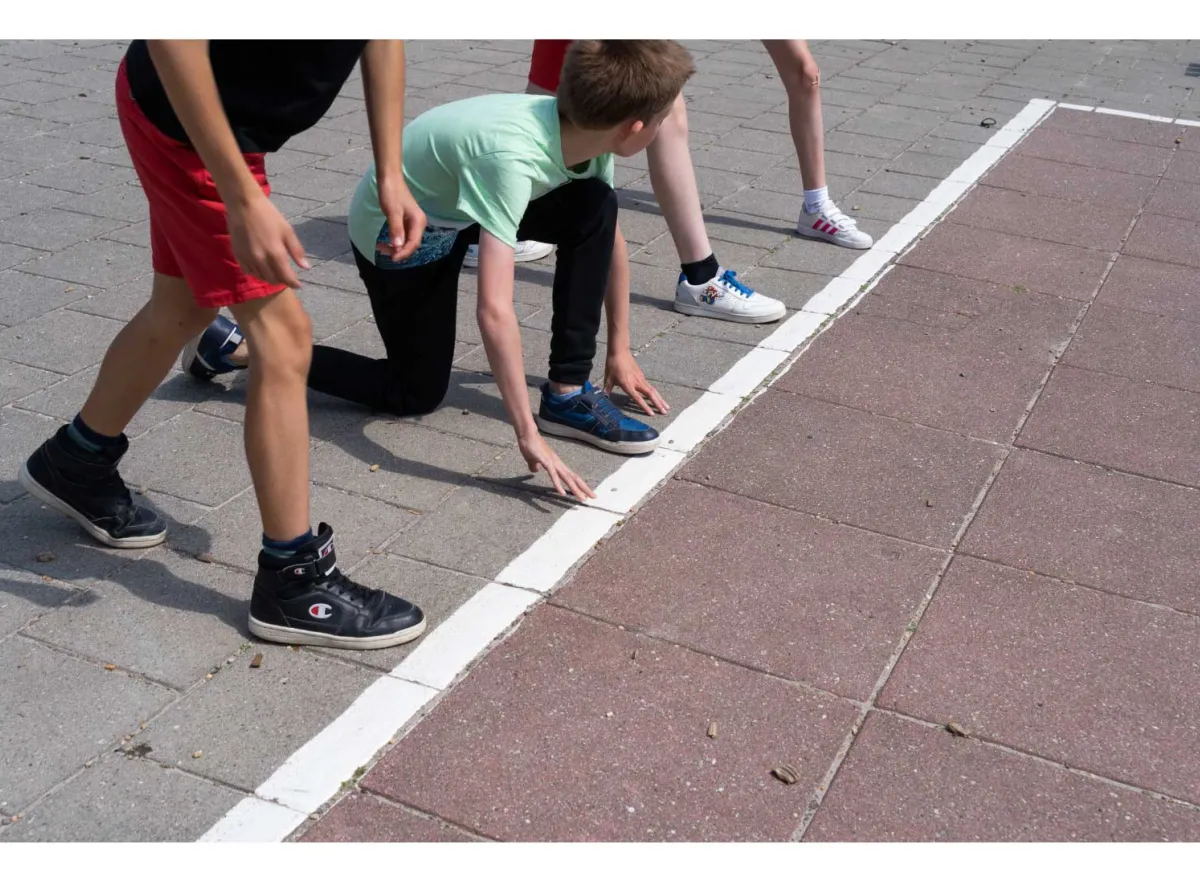 Kinderen staan aan de start van een wedstrijdje lopen op de speelplaats