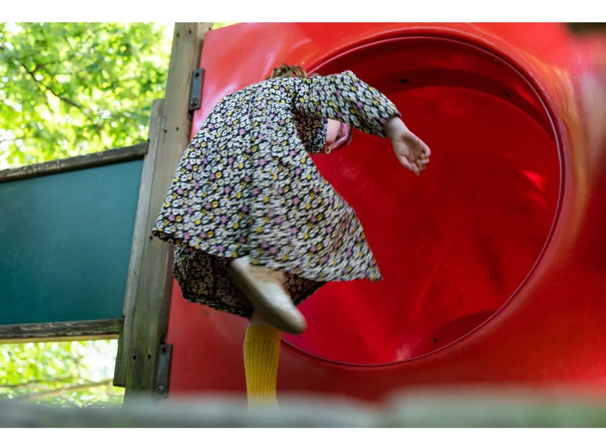 Kind kruipt in rode speelbuis op de speelplaats