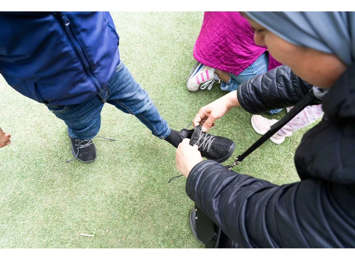 Begeleider knoopt schoenveter van een kind