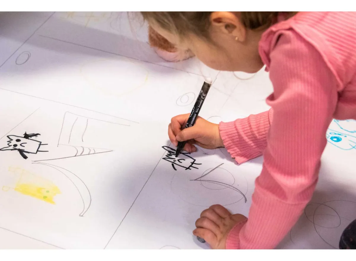 Kind tekent op groot tekenblad op de grond